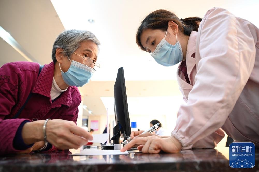 福建省三明市第一医院的医保办工作人员(右)向前来咨询药品报销问题的居民讲解相关政策(2020年11月18日摄)。新华社记者 姜克红 摄